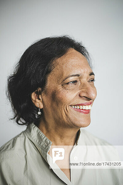 Smiling senior woman looking away against wall