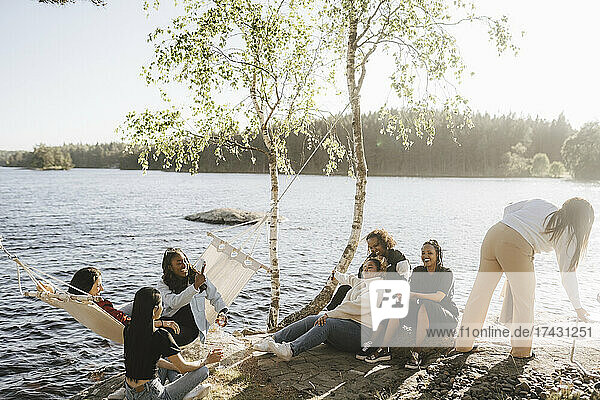 Glückliche Freundinnen genießen am Seeufer an einem sonnigen Tag