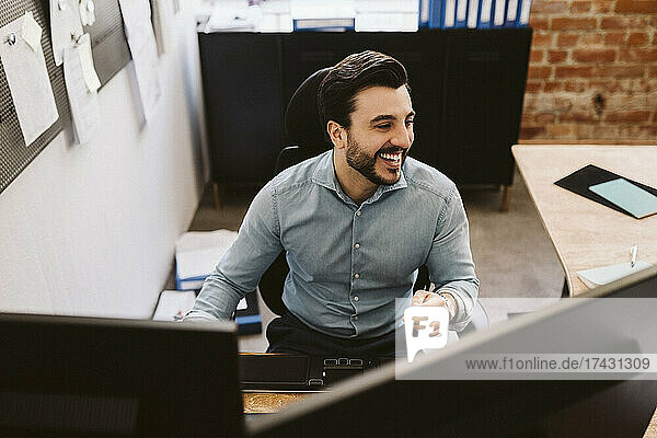 Cheerful business man sitting at desk while looking away