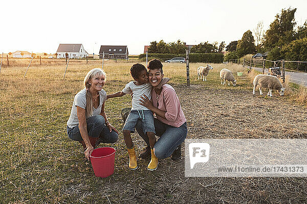 Happy multi-generational family with bucket on field at farm
