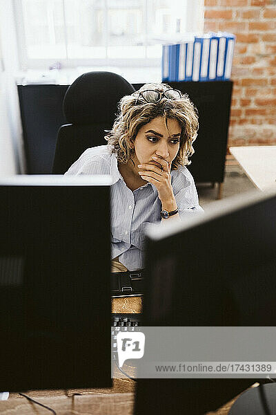 Weibliche Fachkraft schaut auf den Computer  während sie am Schreibtisch im Büro sitzt