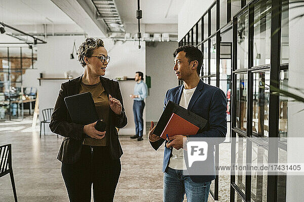 Reife Geschäftsfrau  die mit einem männlichen Fachmann diskutiert  während sie in einem kreativen Büro steht