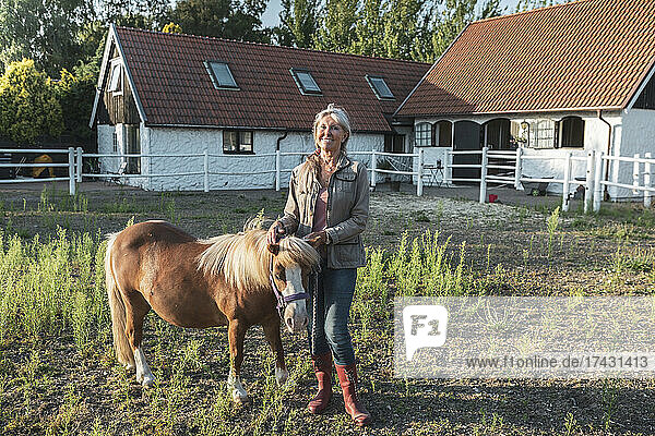 Porträt einer lächelnden älteren Frau mit Pony auf einem Bauernhof
