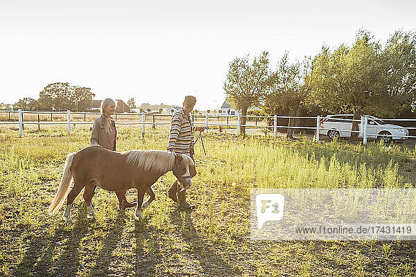 Frau geht mit älterer Mutter und Pferd auf einem Bauernhof spazieren