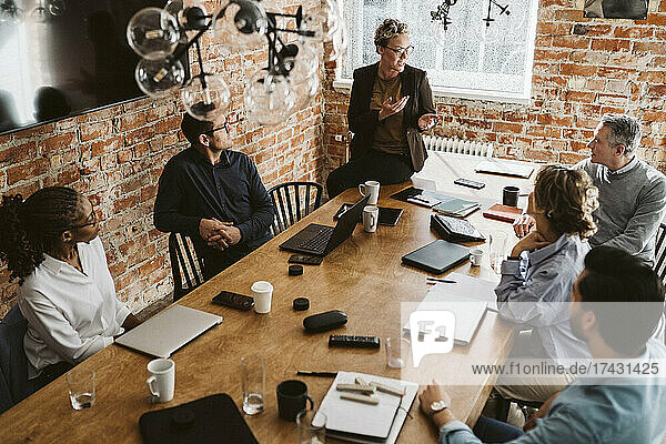 Reife Unternehmerin erklärt Strategie  während sie am Konferenztisch im Büro sitzt