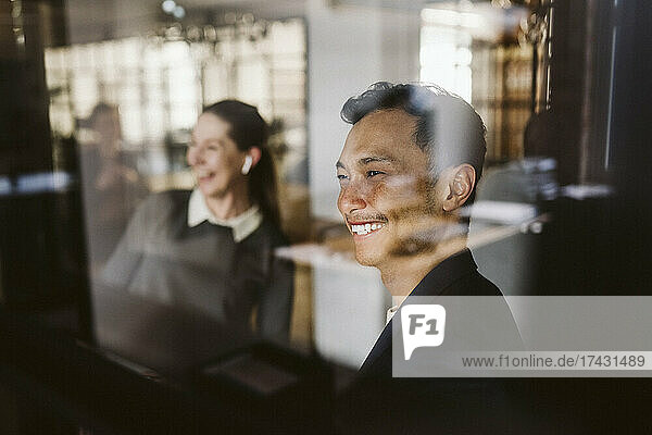 Lachender Mann und lachende Frau durch Glas gesehen