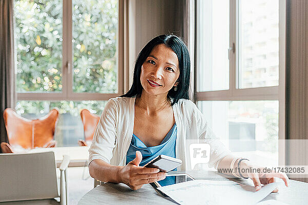 Italy  Portrait of smiling businesswoman at table in creative studio