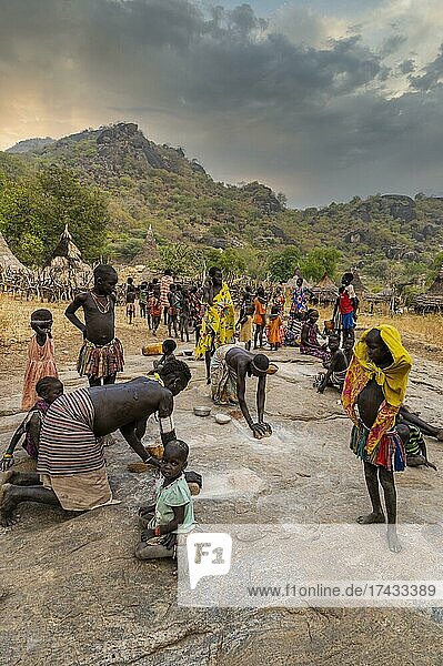 Young girls grinding Sorghum on a rock  Laarim tribe  Boya hills  Eastern Equatoria  South Sudan  Africa