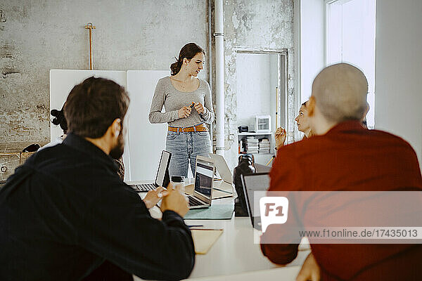 Female entrepreneur discussing with colleagues in startup company