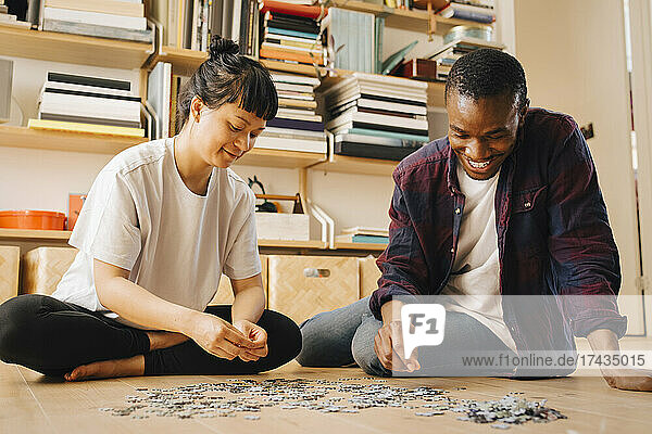 Smiling couple playing jigsaw puzzle on floor at home