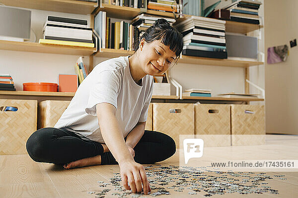 Smiling woman playing jigsaw puzzle in living room