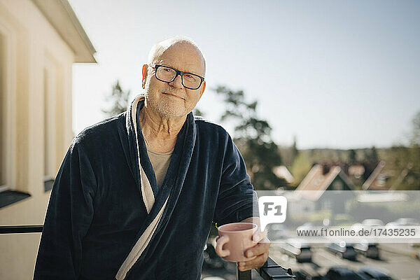 Porträt eines älteren Mannes mit Kaffeetasse auf dem Balkon