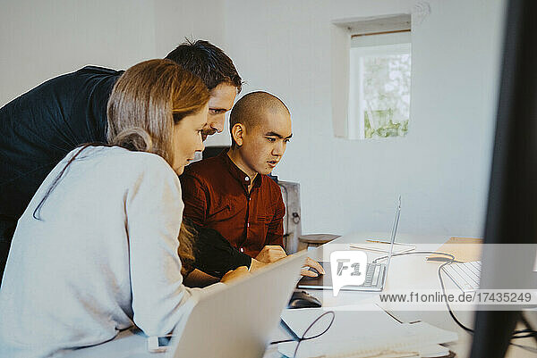 Weibliche und männliche Hacker konzentrieren sich beim Programmieren über einem Laptop im Kreativbüro