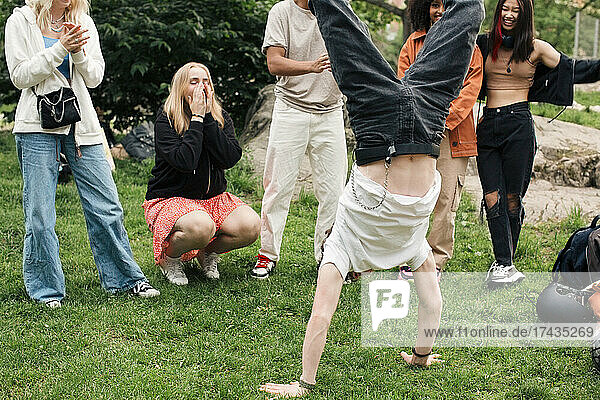 Männlicher Teenager macht Handstand mit Freunden im Park