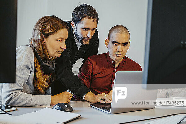 Weibliche und männliche Programmierer  die sich beim Programmieren auf einen Laptop im Büro konzentrieren