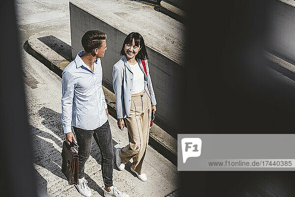 Male and female business professionals walking during sunny day