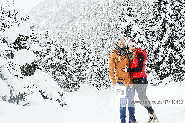 Smiling couple standing together on snow during winter