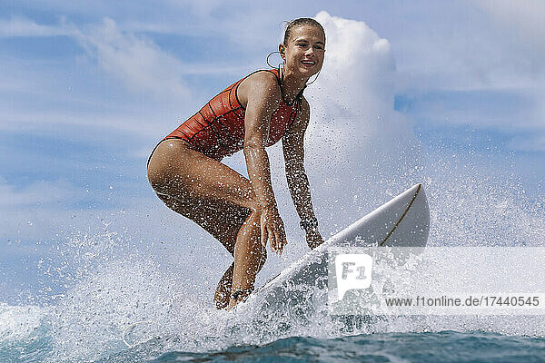 Lächelnde Frau surft im Urlaub an Bord