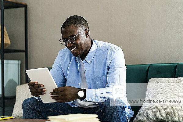 Smiling male freelance worker using digital tablet while working from home
