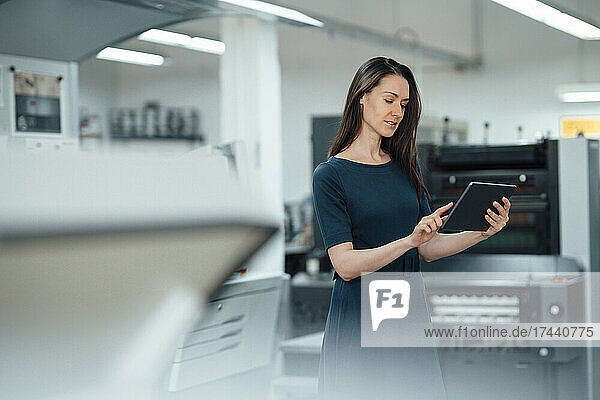 Berufstätige Frau nutzt digitales Tablet  während sie in der Werkstatt steht