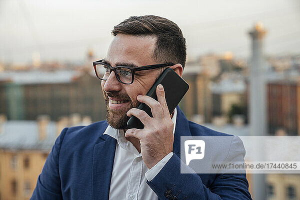 Male professional looking away while talking on smart phone