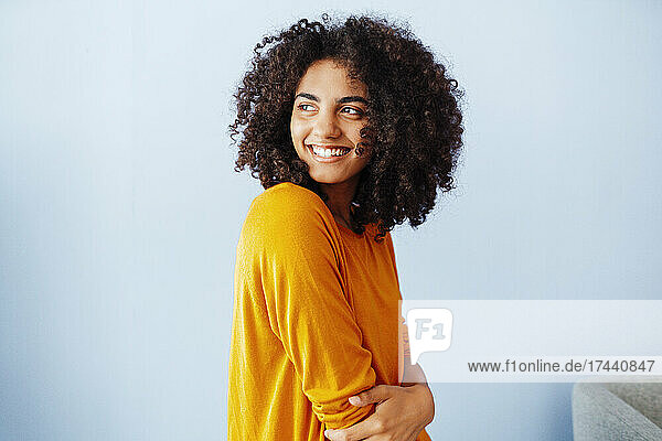 Smiling beautiful woman by wall at home