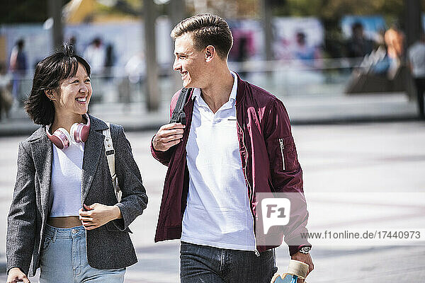 Smiling male and female friends talking during sunny day