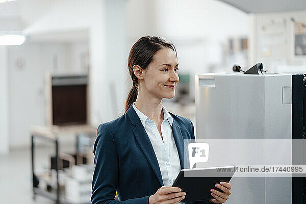 Smiling female business professional with digital tablet in workshop