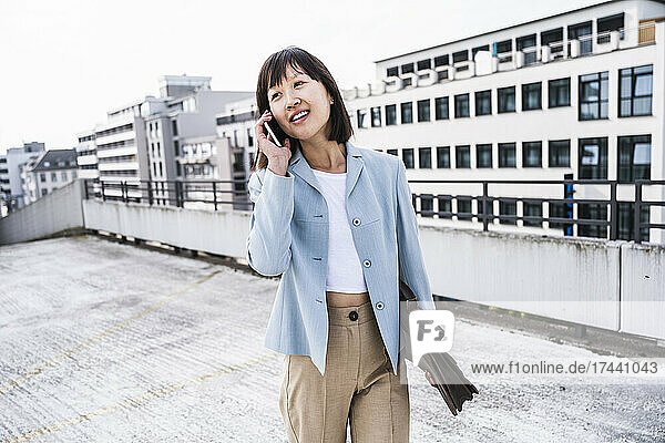 Businesswoman with briefcase talking on mobile phone in city