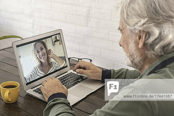 Senior man talking with woman through video call at home