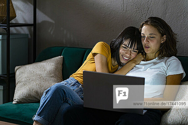 Young lesbian couple sharing laptop in living room