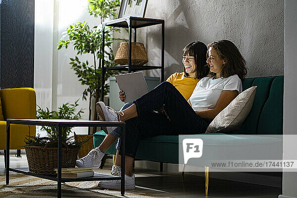 Lächelndes lesbisches Paar  das Laptop im Wohnzimmer teilt