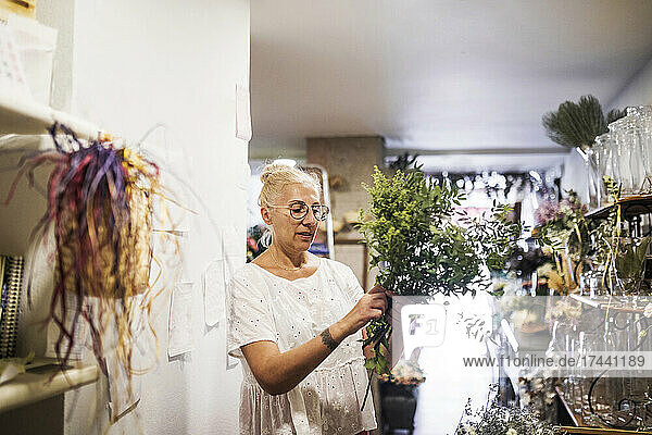 Female florist holding plant while working in flower shop
