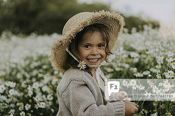 Smiling girl with flower in hat at agricultural field