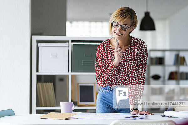 Blonde Geschäftsfrau analysiert Geschäftsplan am Schreibtisch