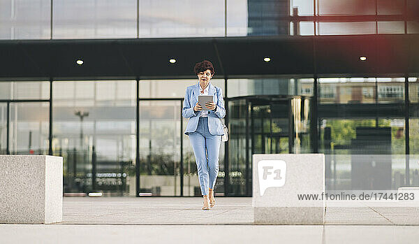 Businesswoman using digital tablet while outside office building