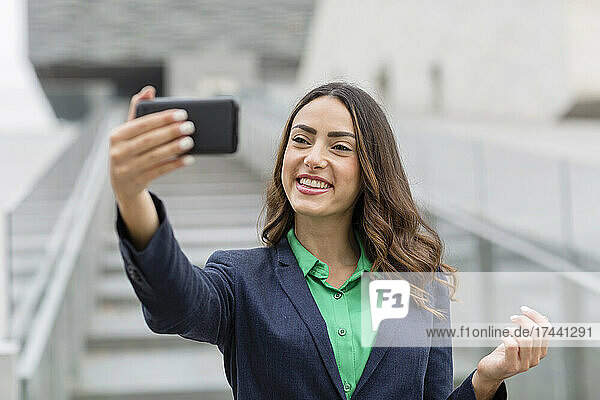 Smiling businesswoman taking selfie through smart phone