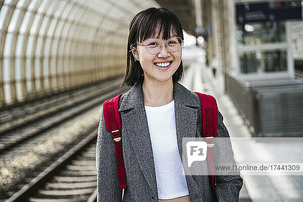 Smiling teenage girl wearing backpack at train station