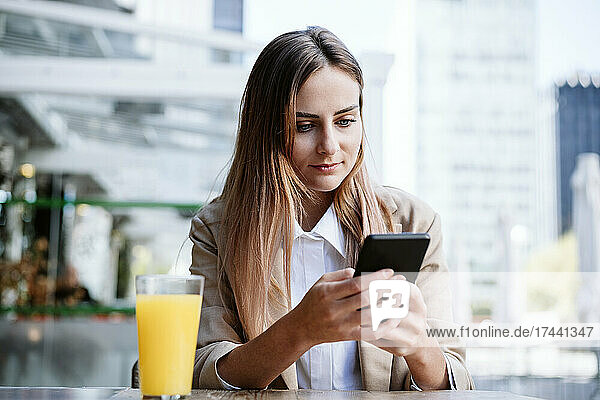 Businesswoman using smart phone at cafe terrace