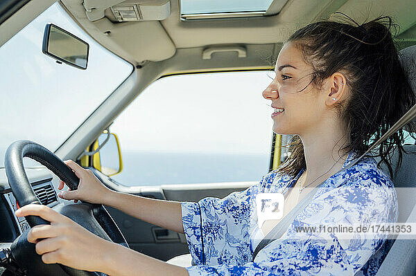 Smiling woman driving camper van during vacation
