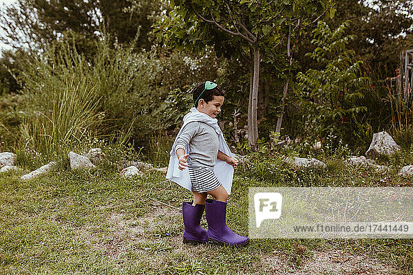 Happy boy wearing purple boots walking on meadow