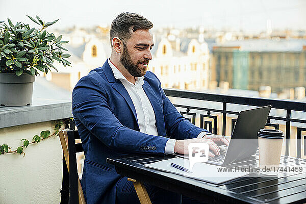 Businessman working on laptop in office balcony