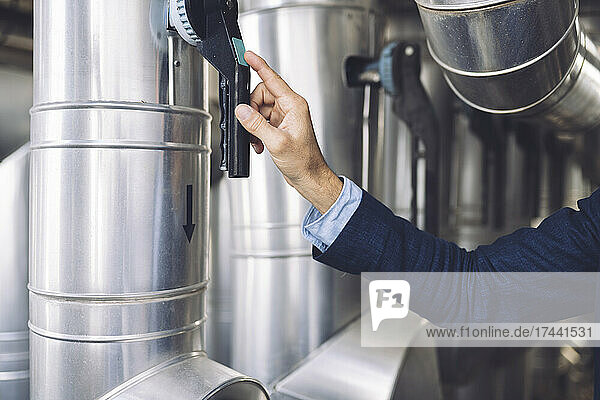 Mature businessman pressing button of machinery in factory