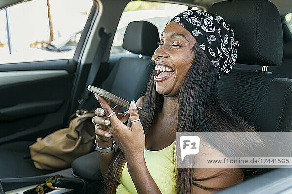 Woman with smart phone laughing in car