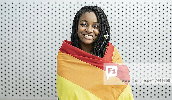 Smiling lesbian woman wrapped in pride flag