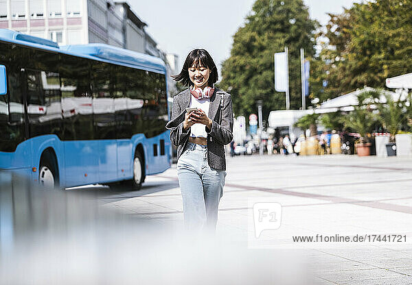 Teenage girl using mobile phone while walking on footpath