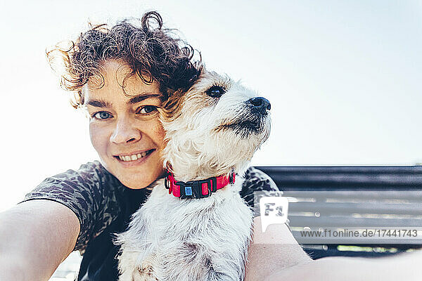 Smiling woman with Jack Russell Terrier taking selfie during sunny day
