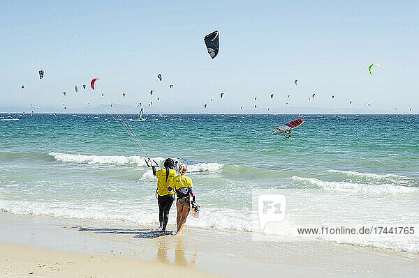 Female instructor giving kiteboard training to woman at beach