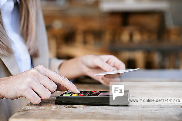 Junge Geschäftsfrau zahlt am Cafétisch mit Kreditkarte