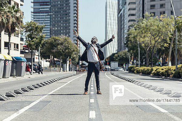 Happy businessman with arms outstretched on street in city